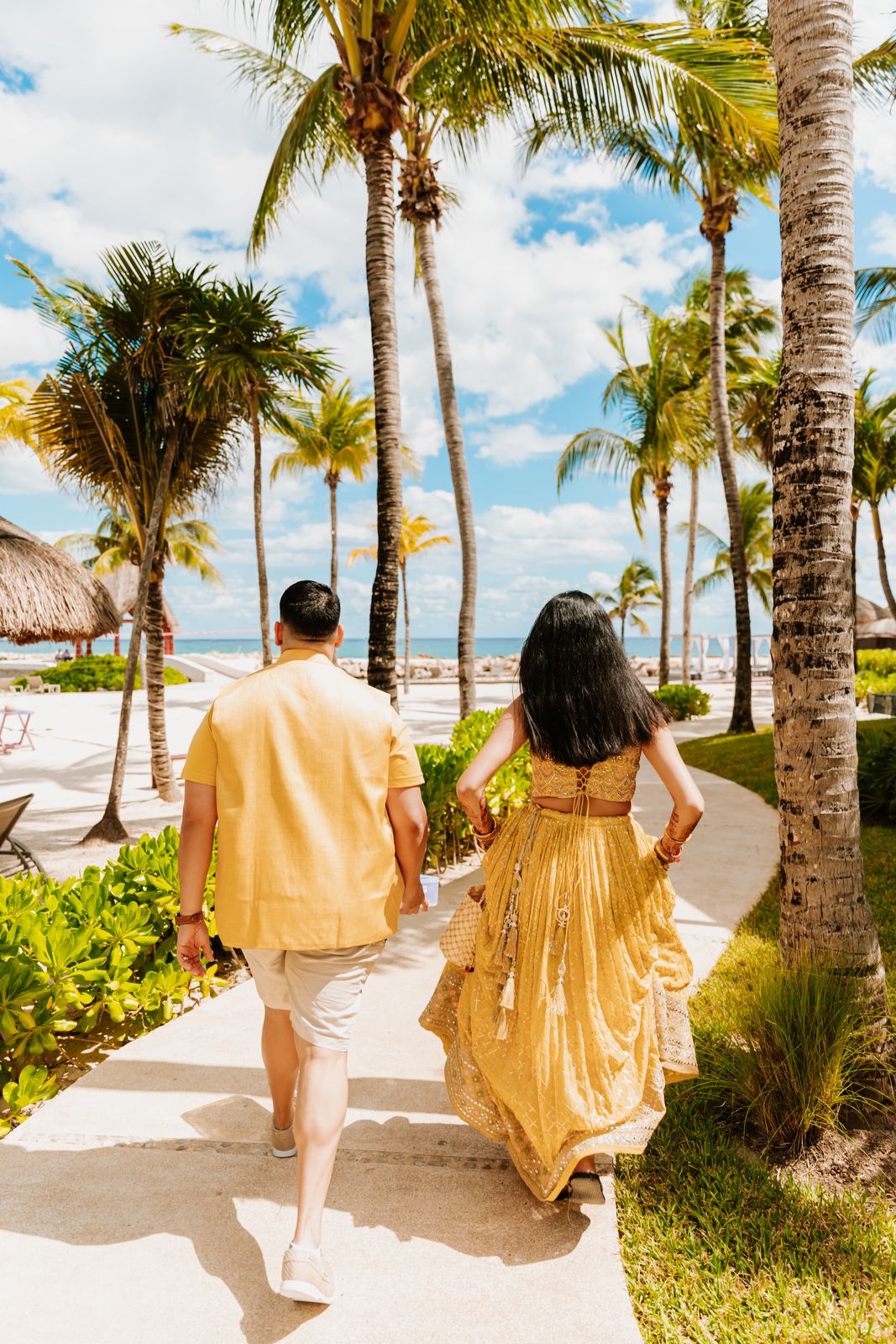 Couple walking a palm-lined path toward the beach