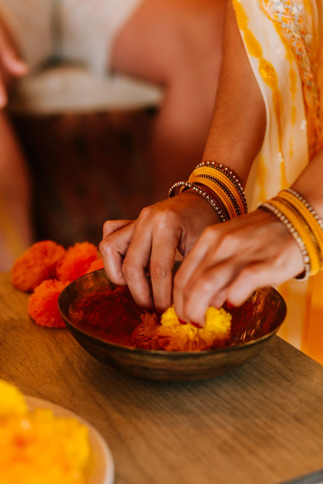 Hands reaching into the bowl of turmeric paste