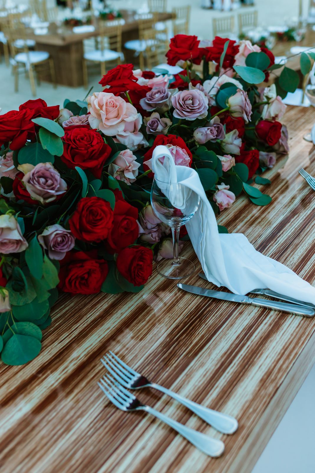 Red and blush roses massed along a wooden table